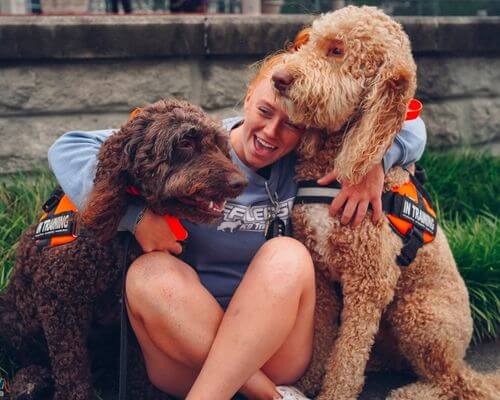 dog trainer hugging two dogs