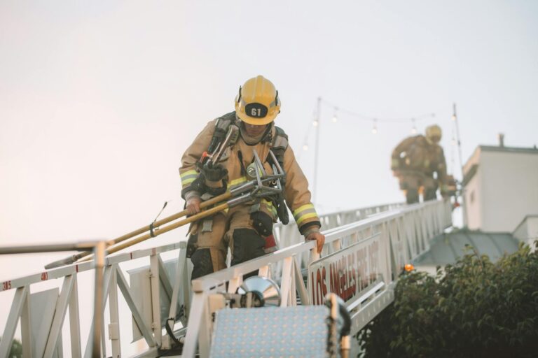 Firefighters in protective gear climbing down a ladder during a rescue operation. Teamwork in action.