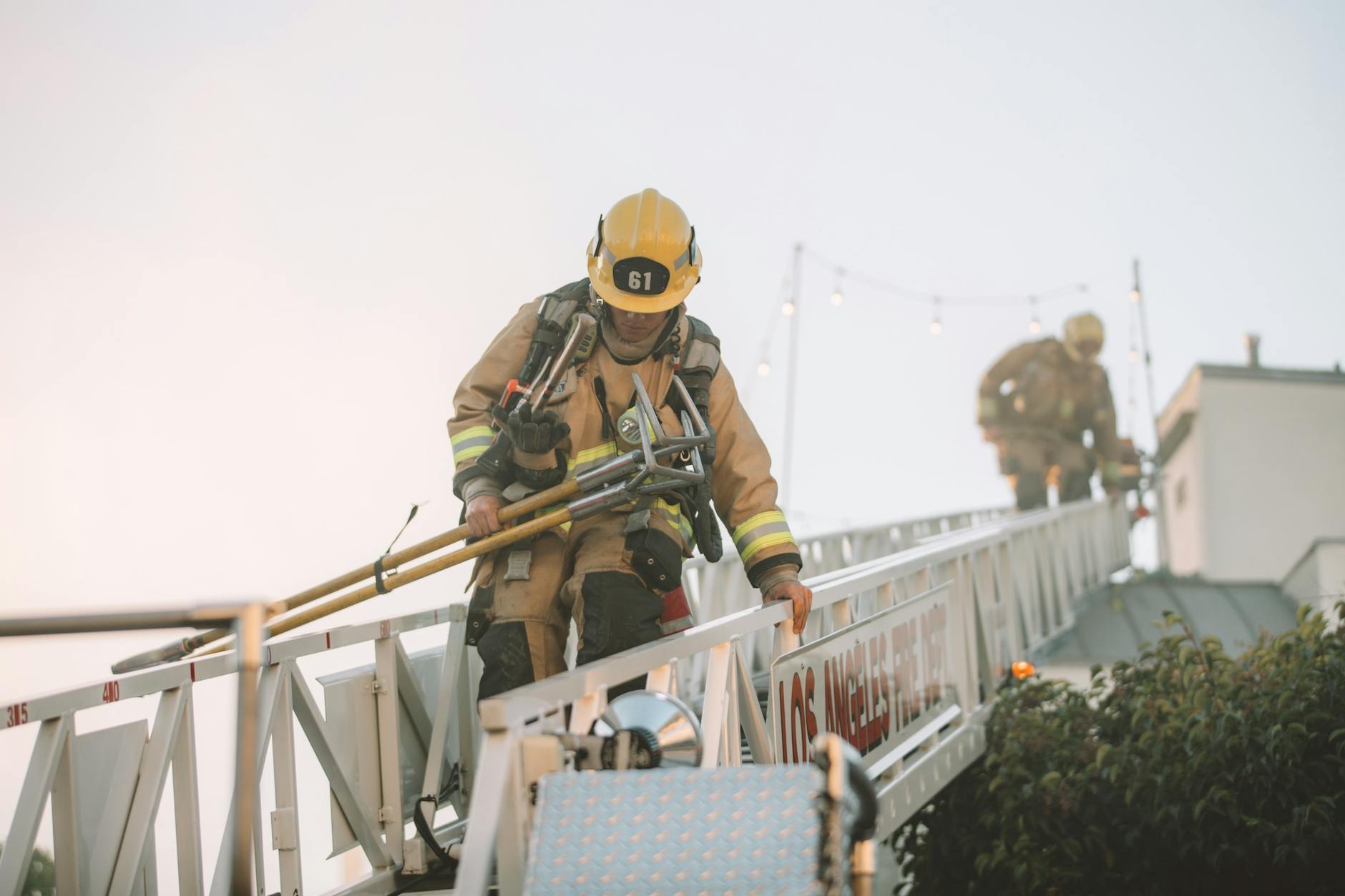 Firefighters in protective gear climbing down a ladder during a rescue operation. Teamwork in action.