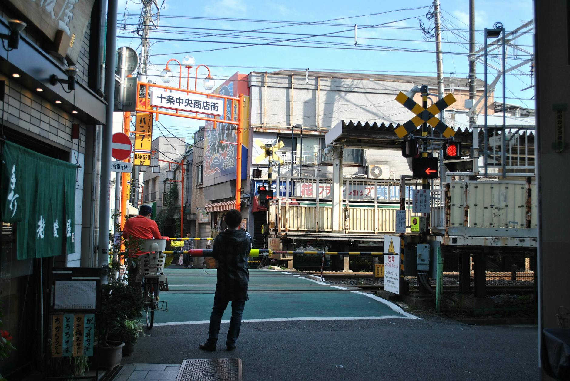 Bustling street scene near a railway crossing in a Japanese city.